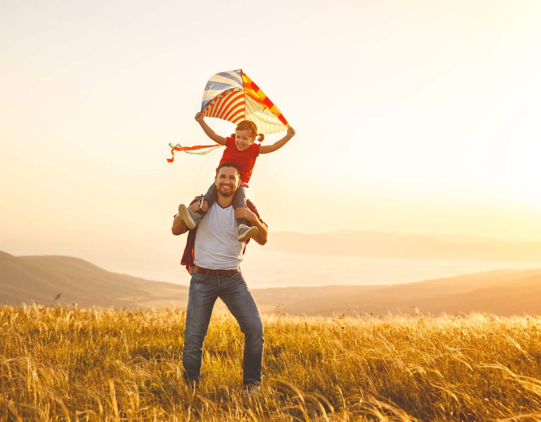 famiglia felice padre e figlia corrono con un aquilone su un prato